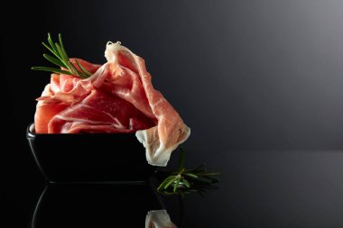 Siyah yansıtıcı arka planda biberiyeli Prosciutto. Boşluğu kopyala.