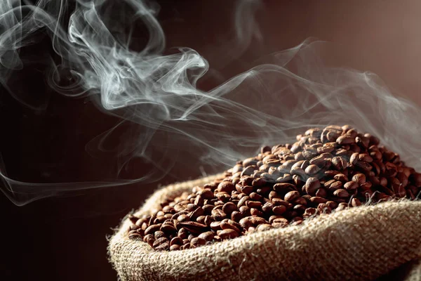 中等程度烘烤的咖啡豆在麻袋里冒着浓烟 — 图库照片