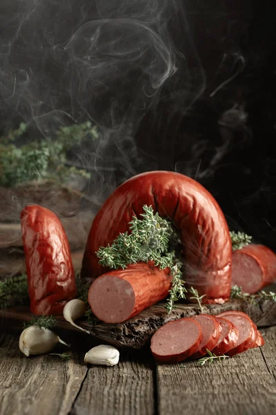 Smoked sausage with thyme and garlic. Sausage in natural smoke on a wooden table.