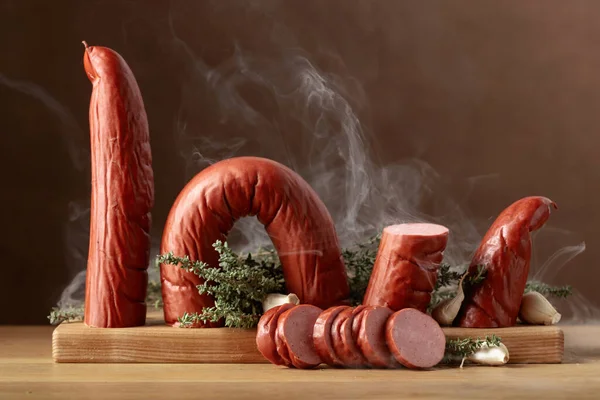 Smoked sausage with thyme and garlic. Sausage in natural smoke on a wooden table.