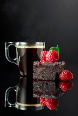 Chocolate cake with fresh raspberries and black coffee on a black reflective background.