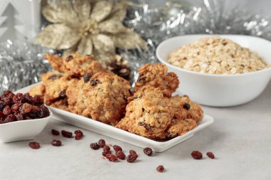 Ev yapımı yulaf ezmeli kurabiye ve Noel süslemeleri olan bir masada kuru üzüm..