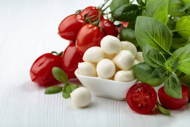 Beyaz ahşap bir masada fesleğen ve domatesli Mozzarella peyniri..