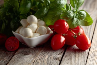 Eski ahşap bir masada fesleğenli ve domatesli Mozzarella peyniri. Geleneksel İtalyan atıştırması.