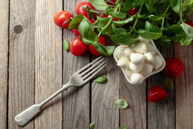 Eski ahşap bir masada fesleğenli ve domatesli Mozzarella peyniri. Geleneksel İtalyan yemeği. Boşluğu kopyala.