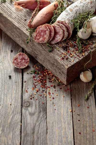 Traditional dry-cured sausage with thyme, garlic, onion, and spices. Dry-cured sausage on a old wooden table. Copy space.