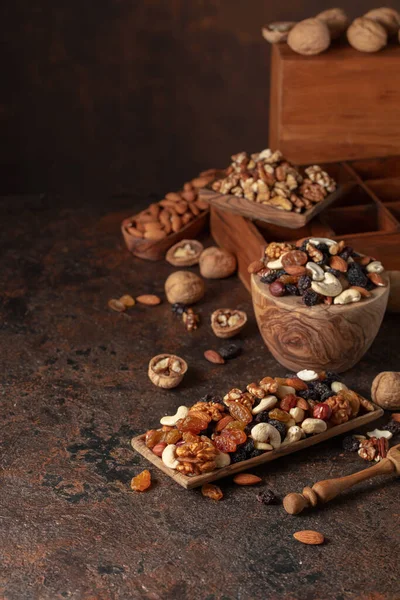 Mix of nuts and raisins on a brown rustic background. Presented raisins, walnuts, hazelnuts, cashews, pecans, and almonds.
