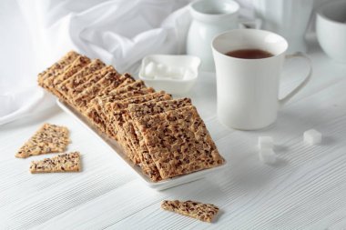 Beyaz ahşap bir masada ayçekirdeği ve keten tohumlu çıtır krakerler..