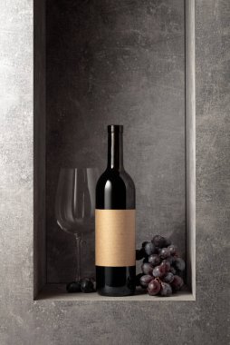 Mavi üzümlü bir şişe ve bir bardak kırmızı şarap. Şişede eski boş etiket var. Boşluğu kopyala.