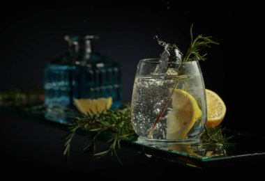 Limon ve biberiyeli cin tonik kokteyli. Limon dilimi bardağa dökülür Kokteylle.