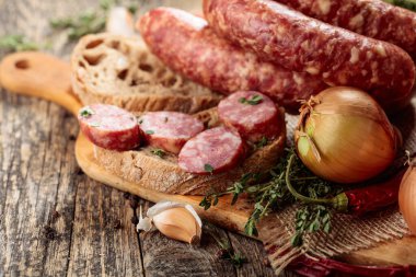 Kurutulmuş sosis, kekik, soğan, sarımsak ve biber. Eski ahşap bir masada sosis ve baharat..