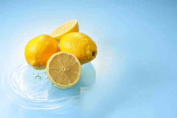 Ripe juicy lemons on a blue background with water splashes. Copy space.