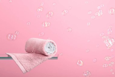 Cam bir rafta havlu. Kabarcıklı pembe arka plan. Banyo ve hijyen teması. Boşluğu kopyala.