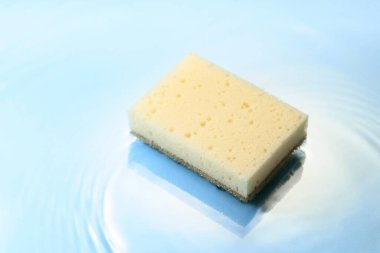 New and clean sponge falls into the water forming waves. Clean concept. 