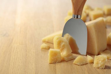 Parmesan cheese and knife on a wooden cutting board.