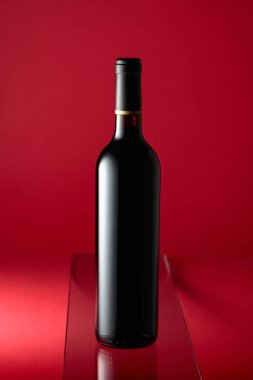 kırmızı bir arka plan üzerinde kırmızı şarap şişe.