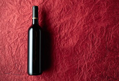 Bottle of red wine on a background of the old red crumpled paper. Top view.