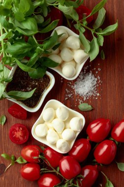 Eski ahşap bir masada fesleğen, pesto sosu ve domatesli Mozzarella peyniri. Geleneksel İtalyan atıştırması.