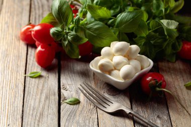 Eski ahşap bir masada fesleğenli ve domatesli Mozzarella peyniri. Geleneksel İtalyan atıştırması.