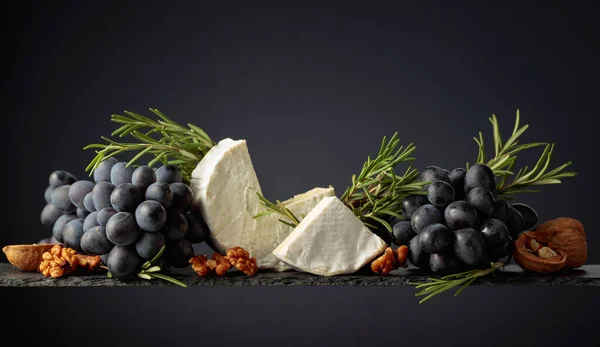 Ser Camembert Orzechami Włoskimi Niebieskimi Winogronami Rozmarynem Czarnym Tle — Zdjęcie stockowe