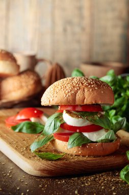 Eski ahşap bir masada mozarella, domates ve fesleğenli sandviç..