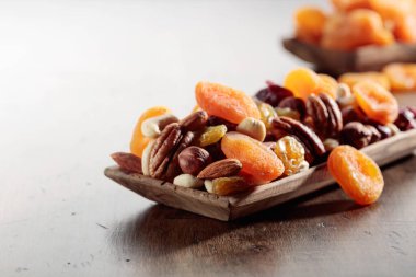 Eski ahşap bir masada fındık ve kurutulmuş meyve karışımı. Sunulan kayısılar, kuru üzümler, cevizler, fındıklar, cevizler, cevizler ve bademler..