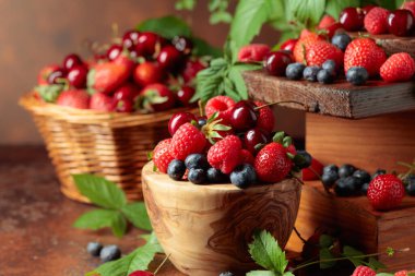 Yapraklı taze böğürtlen. Eski bir masada çilek, ahududu, yabanmersini ve tatlı kirazlar.. 