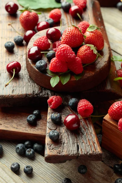 Yapraklı taze böğürtlen. Çilek, ahududu, böğürtlen ve kirazlar eski ahşap bir masada.. 