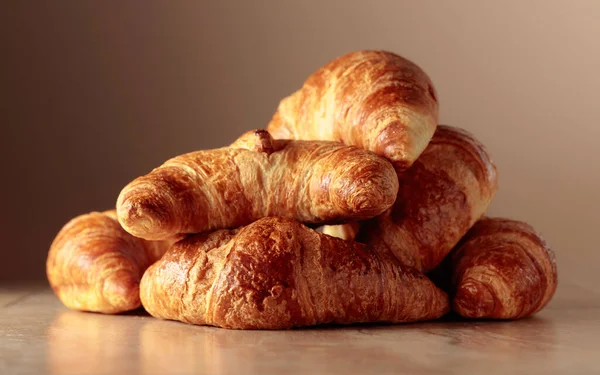 Freshly baked croissants on a beige ceramic table. Traditional French kitchen.