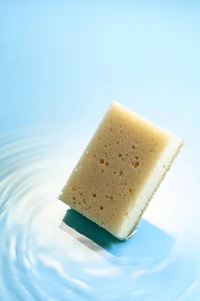 New and clean sponge falls into the water forming waves. Clean concept. Copy space.