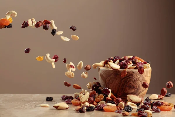 Flying dried fruits and nuts. The mix of nuts and raisins in a wooden bowl. Copy space.