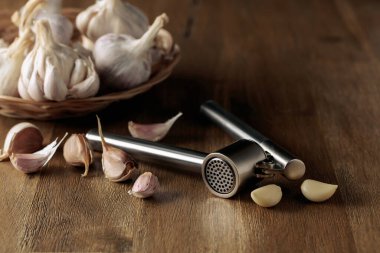 Garlic bulbs and garlic press on an old wooden table. 