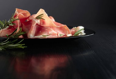 İtalyan jambonu ya da siyah tabakta biberiyeli İspanyol jamonu. Seçici odaklanma. Boşluğu kopyala. 