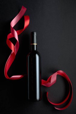 Bottle of red wine with red and pink satin ribbons. Top view. Copy space.