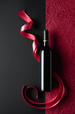 Bottle of red wine with red and pink satin ribbons. Top view.