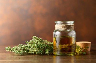 Eski ahşap bir masada taze kekik ile bir şişe kekik yağı. Boşluğu kopyala.