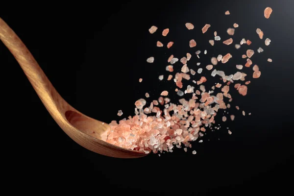 ピンクのヒマラヤ塩は木製のスプーンで注ぎます 暗い背景にヒマラヤ塩 スペースのコピー — ストック写真