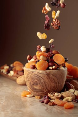 Uçan kurutulmuş meyve ve fındık. Tahta bir kasede fındık ve kuru üzüm karışımı..