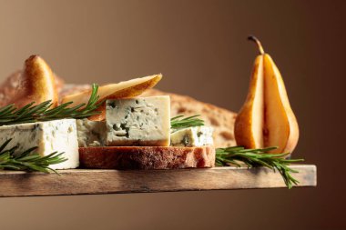 Mavi peynirli, armutlu ve biberiyeli sandviç. Eski ahşap bir masada ciabatta, mavi peynir, armut ve biberiye.