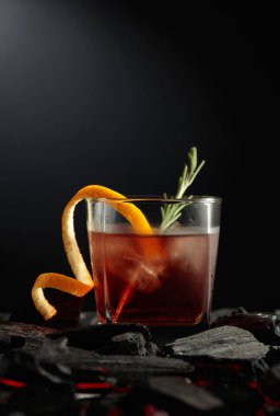 Buzlu, portakal kabuklu ve biberiyeli eski moda kokteyl. Yanan kömürle kokteyl bardağı. Boşluğu kopyala.