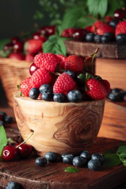 Yapraklı taze böğürtlen. Eski bir masada çilek, ahududu, yabanmersini ve tatlı kirazlar.. 
