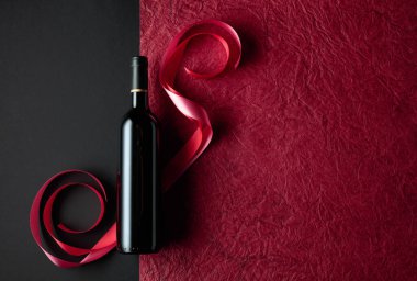 Bottle of red wine with red and pink satin ribbons. Top view.