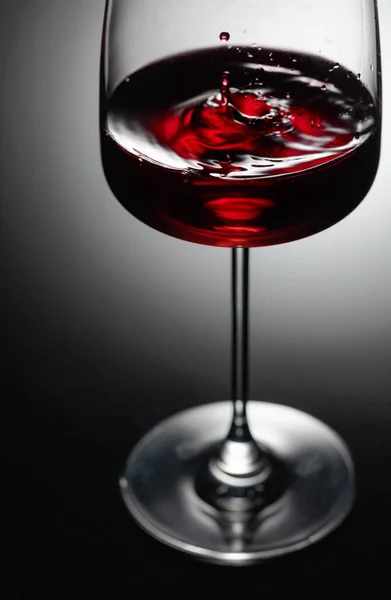 Druppel Rode Wijn Valt Een Wijnglas Zwarte Achtergrond Achtergrondverlichting — Stockfoto