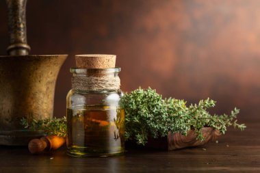 Eski ahşap bir masada taze kekik ile bir şişe kekik yağı. Boşluğu kopyala.