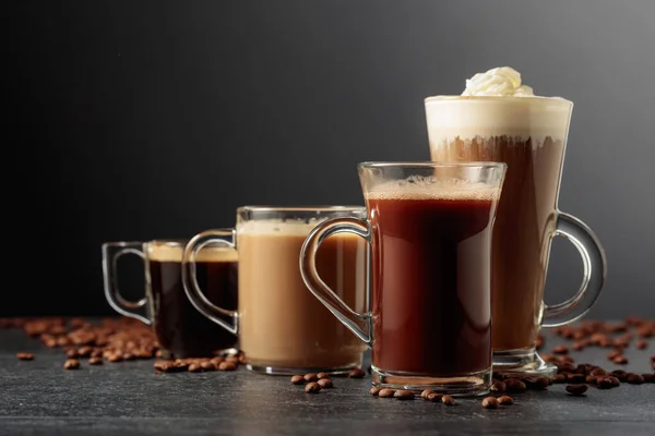 Olika Kaffe Och Chokladdrycker Med Spridda Kaffebönor Ett Svart Bord — Stockfoto