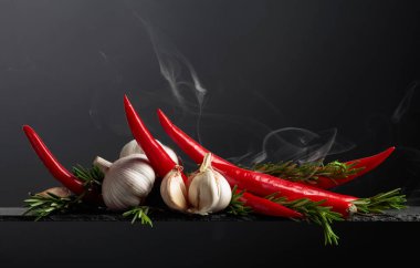 Kırmızı kırmızı biber, sarımsak ve biberiye siyah arka planda. Boşluğu kopyala..