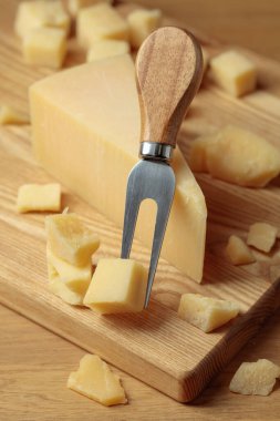 Parmesan cheese and fork on a wooden cutting board.