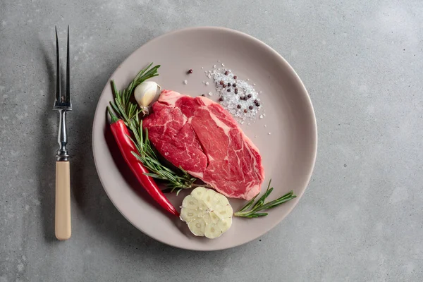 ローズマリー ニンニク コショウで焼くための生の牛肉ステーキ 灰色の具体的な背景 トップ表示 — ストック写真