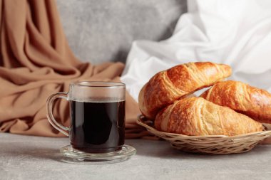 Freshly baked croissants and black coffee on a kitchen table.