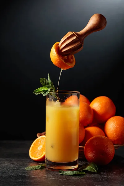 Orange juice is squeezed from fresh fruit. Juice is poured into a glass with ice. The concept of natural organic food.